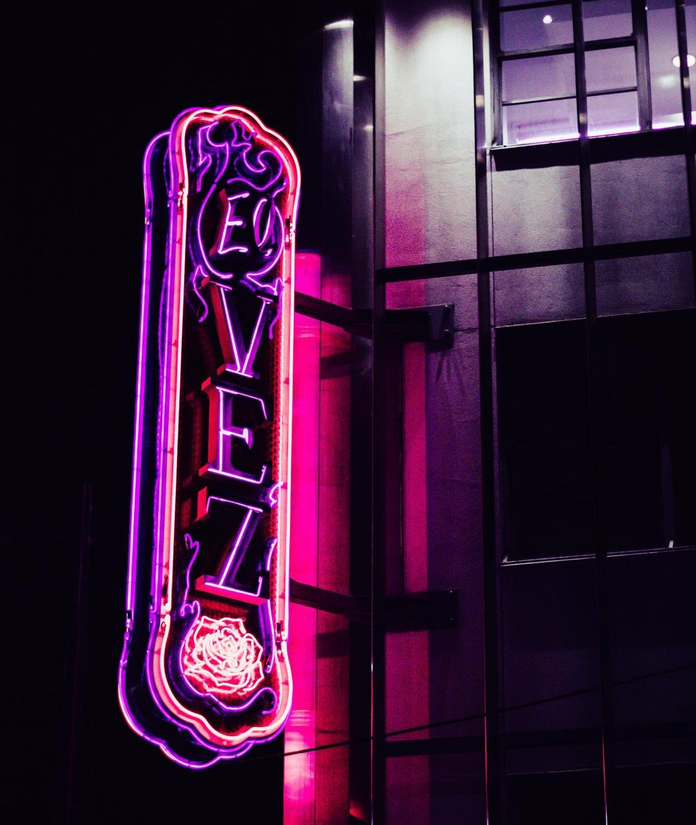 Neon sign for a restaurant with purple and pink lights, reading "Velz" with a rose design.
