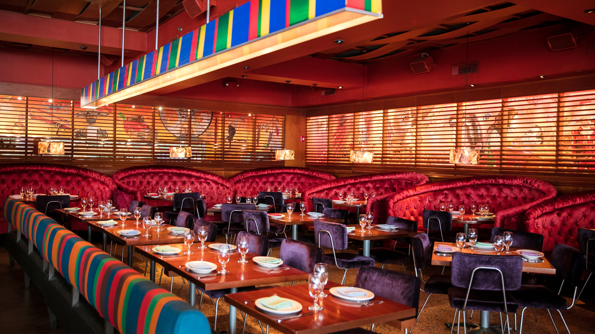 Colorful restaurant interior with patterned booths, red walls, and wooden tables set for dining.