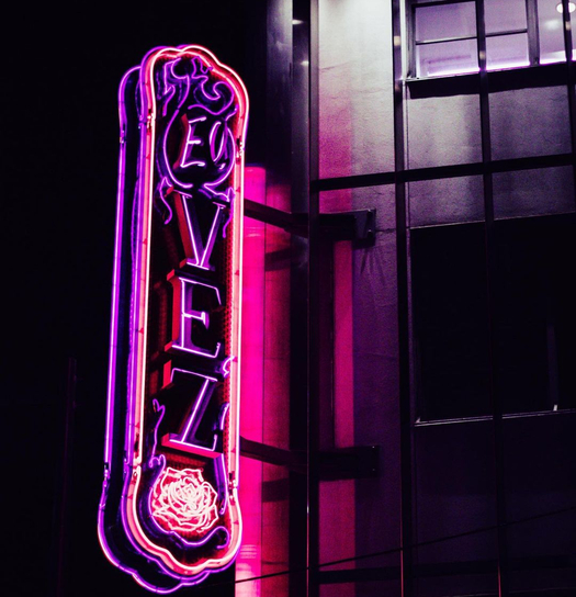 Colorful wall display with miniature scenes, religious symbols, and figures in a storefront setting.