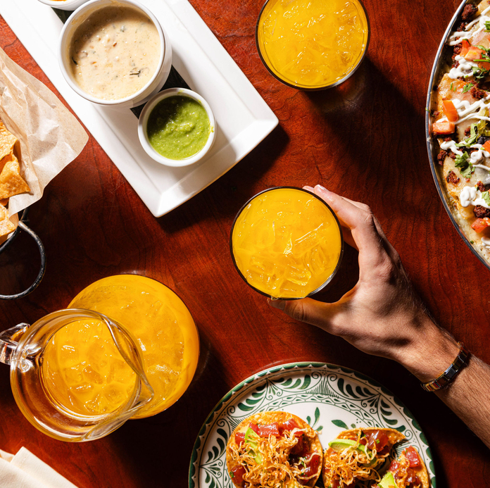 A hand holds a glass plate with a small dessert topped with whipped cream and garnished with strawberries.